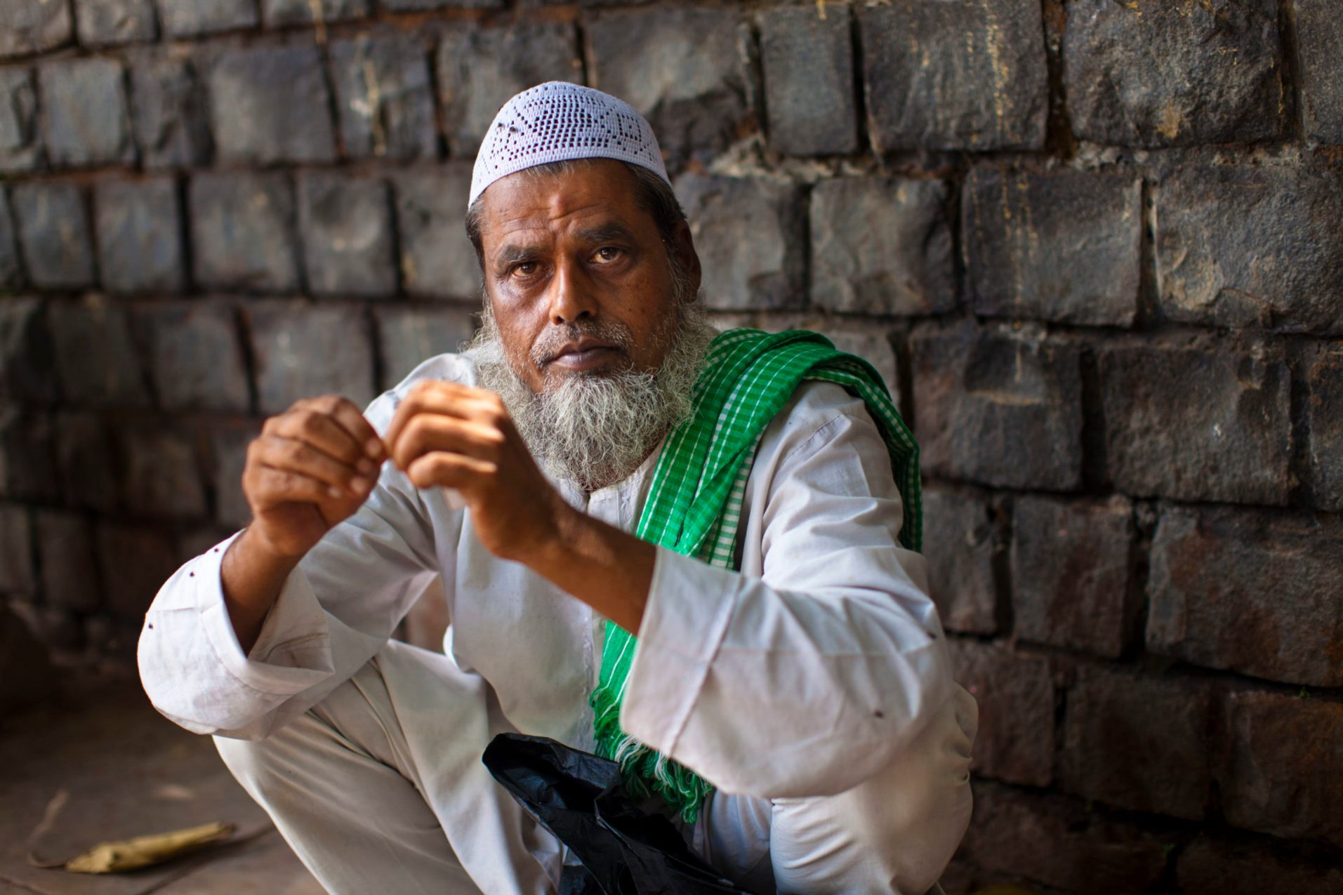 A Muslim man squats in the street in Old Delhi.